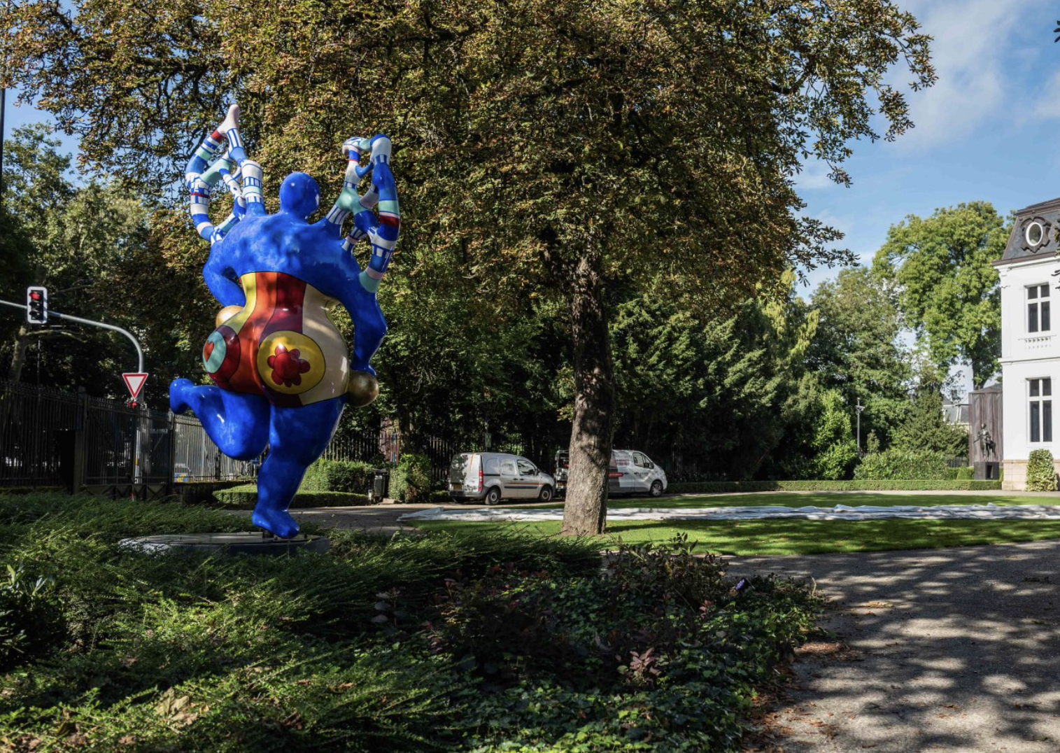 colorful painted polyester sculpture by Niki DE Saint Phalle in the shape of an angel installed in a lush green garden at Villa Vauban in Luxembourg