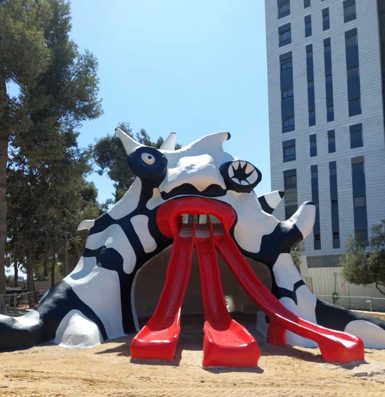 black and white cement sculpture of a monster with three red tongues